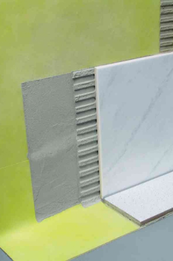 Étanchéité d’une douche sous carrelage avec membrane jaune, mortier-colle et pose de carreaux effet marbre.