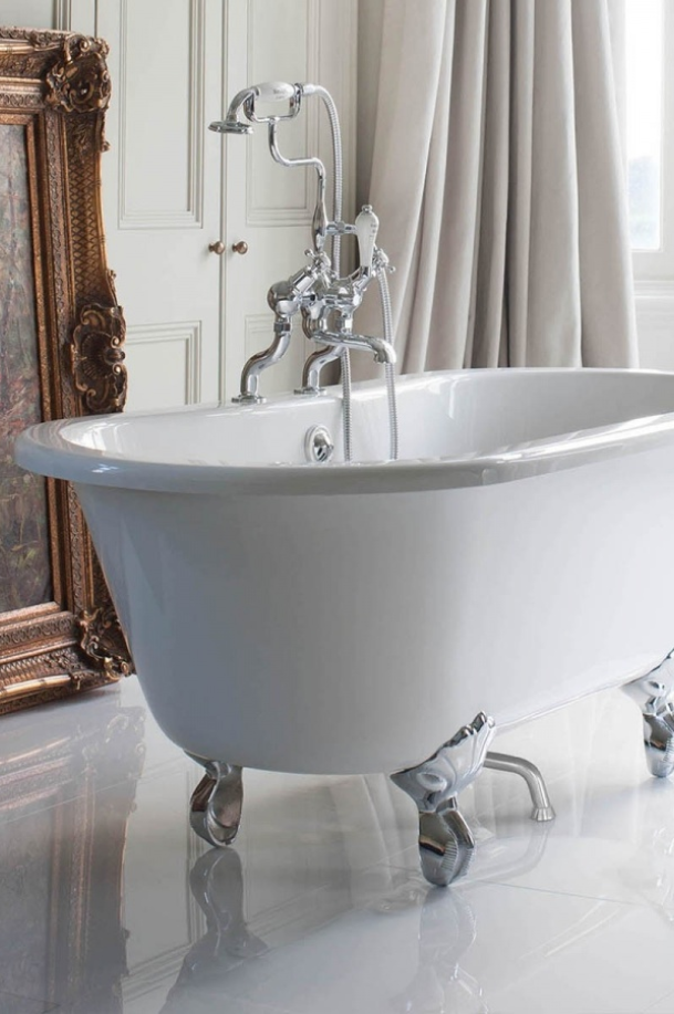 Baignoire îlot blanche de style rétro sur pieds de lion chromés, avec robinetterie sur gorge et douchette à main, dans une salle de bains élégante.