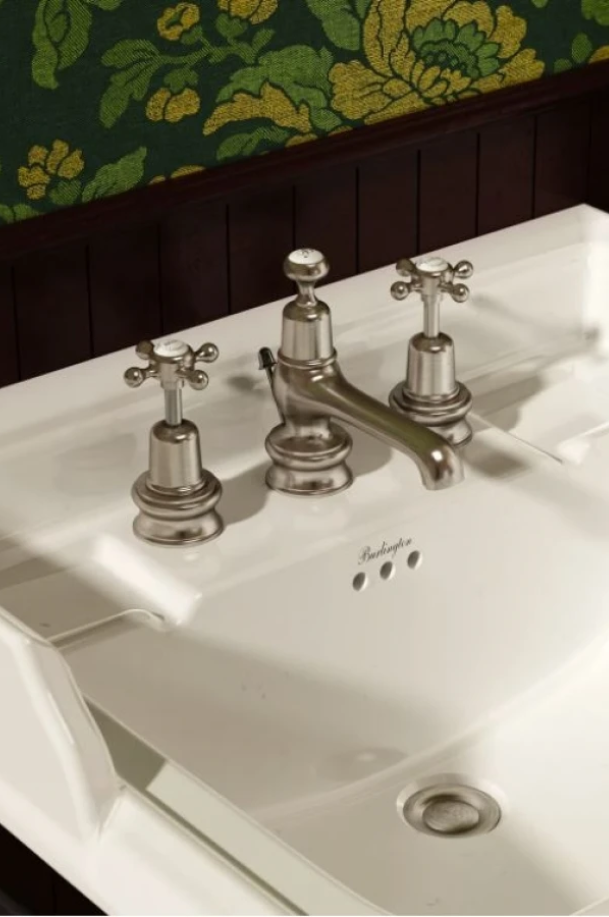 Robinet de lavabo rétro à trois trous en finition métal argenté, avec deux poignées à croisillons, installé sur un lavabo blanc de style classique.