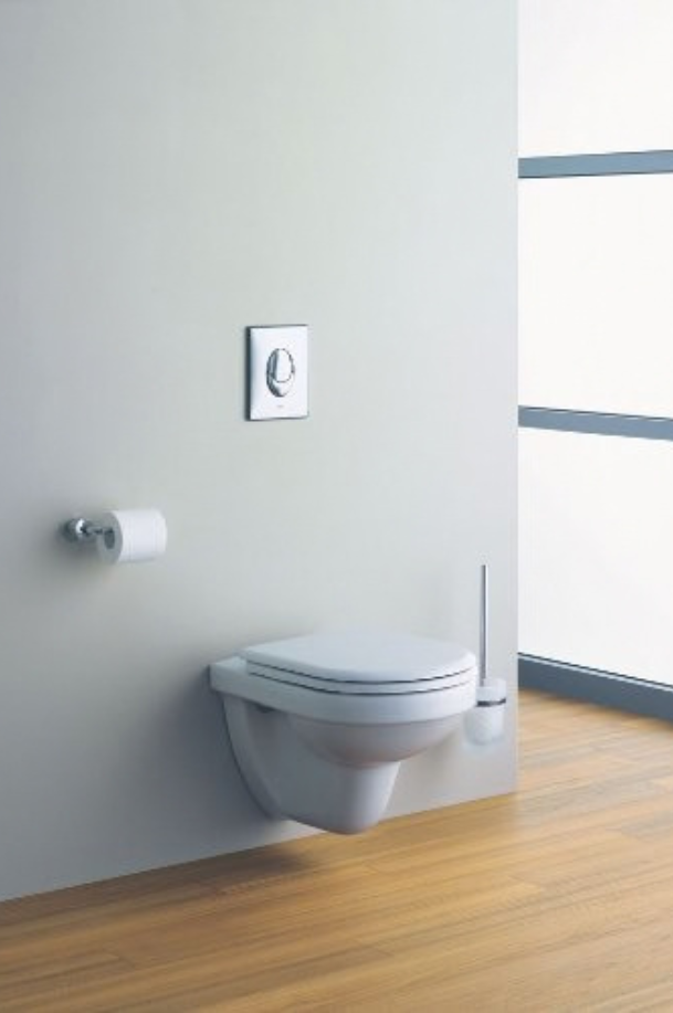 WC suspendu blanc avec plaque de commande double chasse chromée GROHE, porte-papier toilette mural et brosse WC, dans des toilettes modernes.