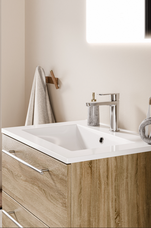 Meuble de salle de bains en bois clair avec tiroirs, plan vasque blanc rectangulaire et robinetterie chromée.